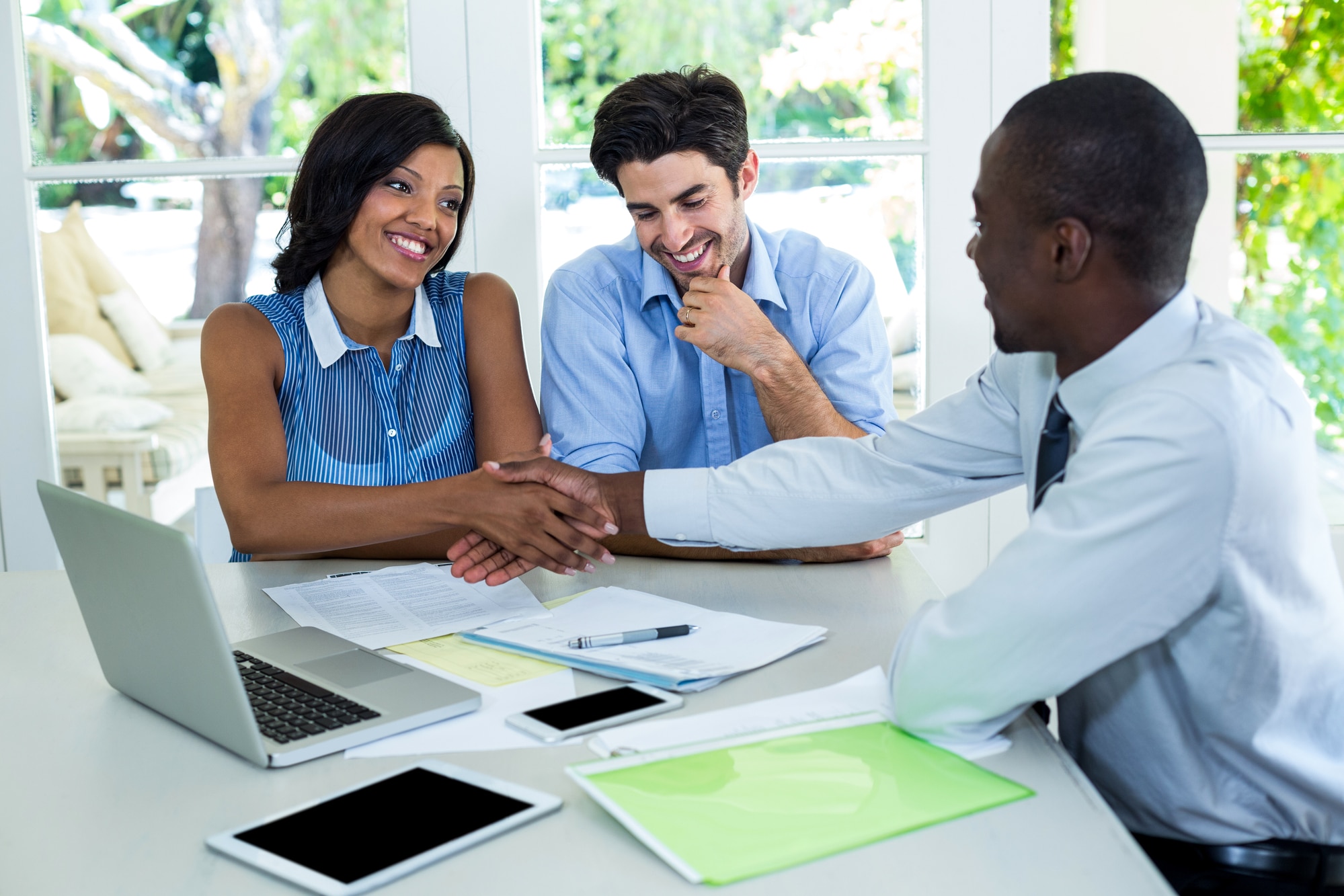 Happy couple shaking hands with real estate agent at home