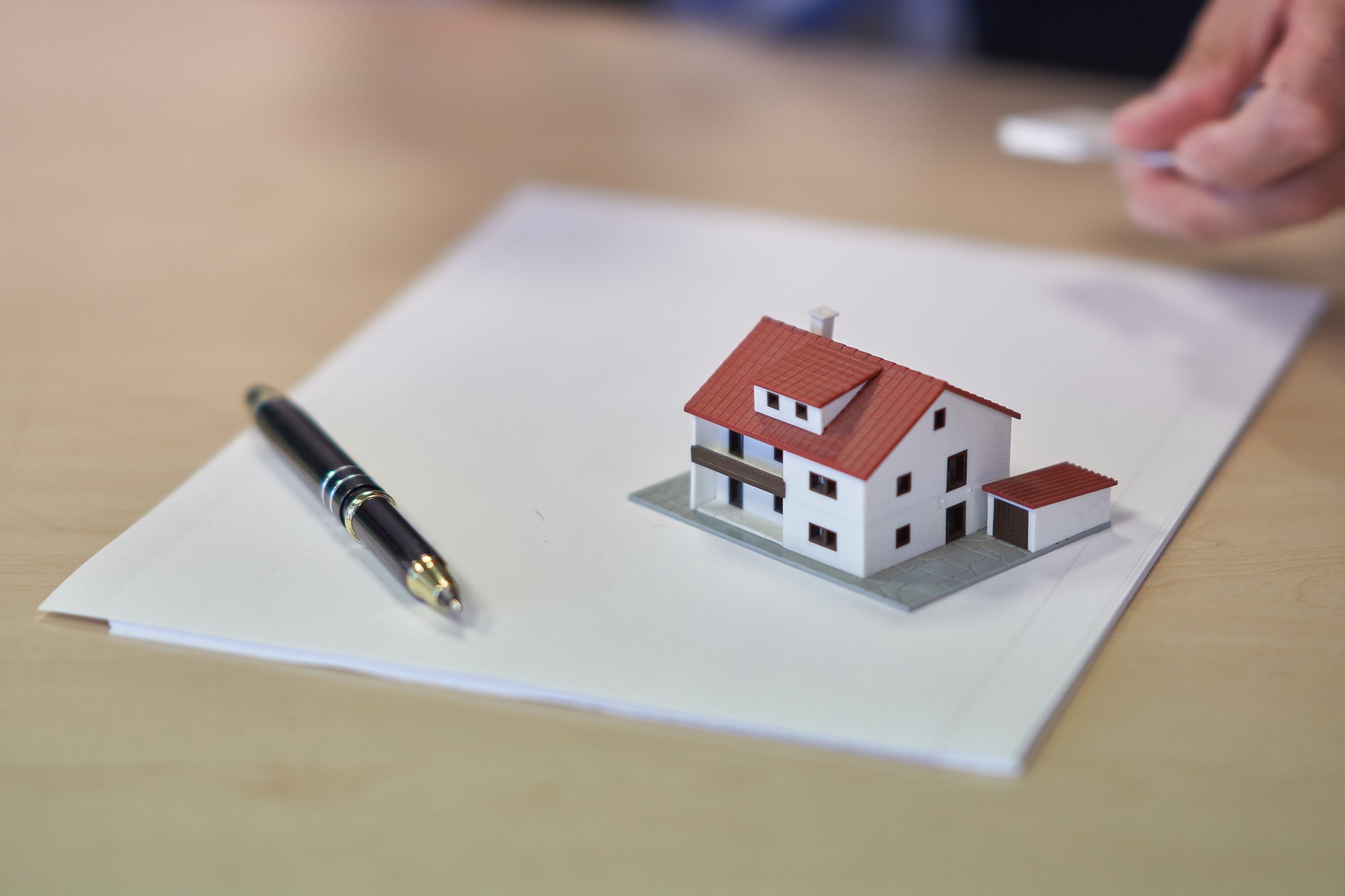 Miniature house and pen on top of a blank document