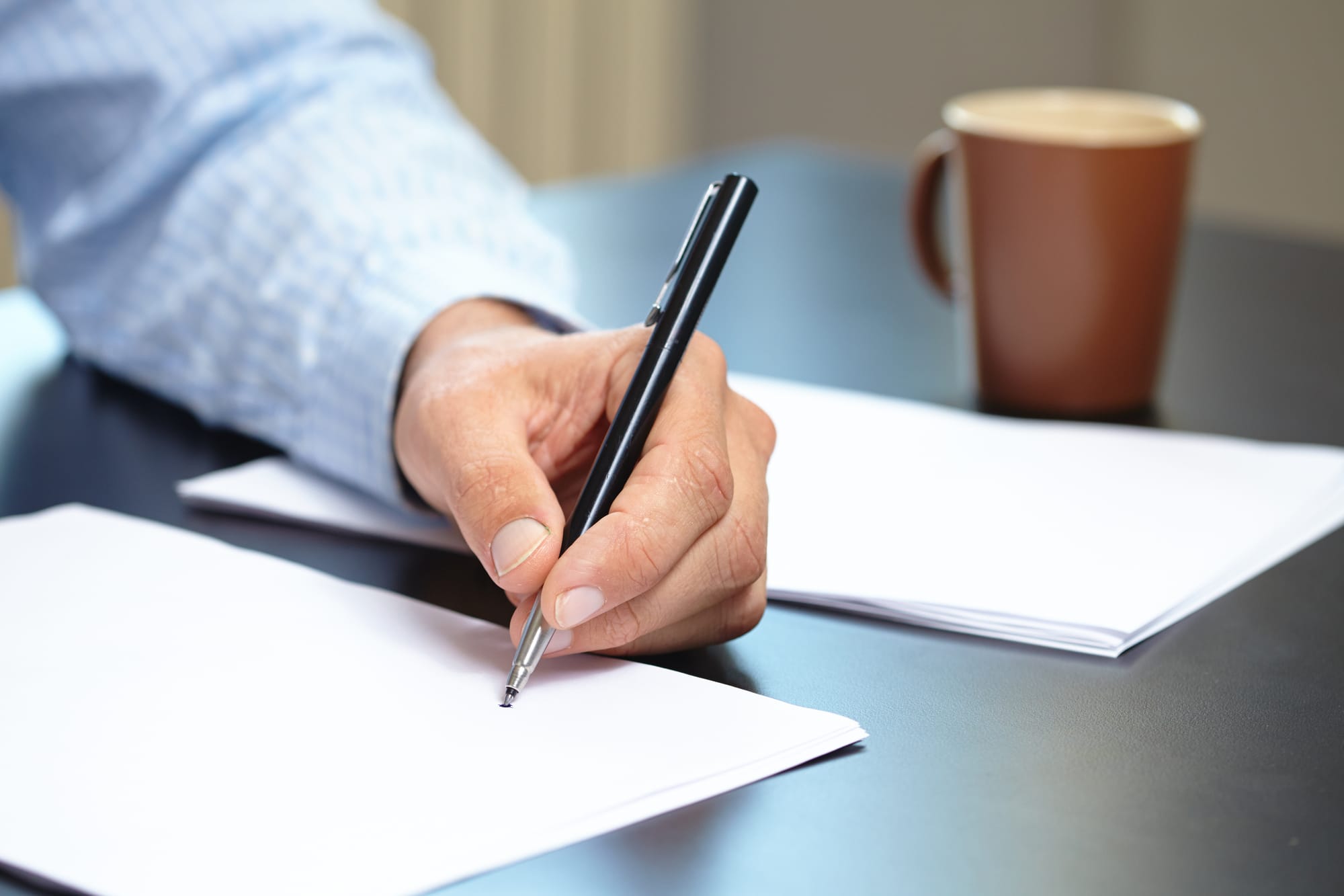 Man writing on a blank document with a pen